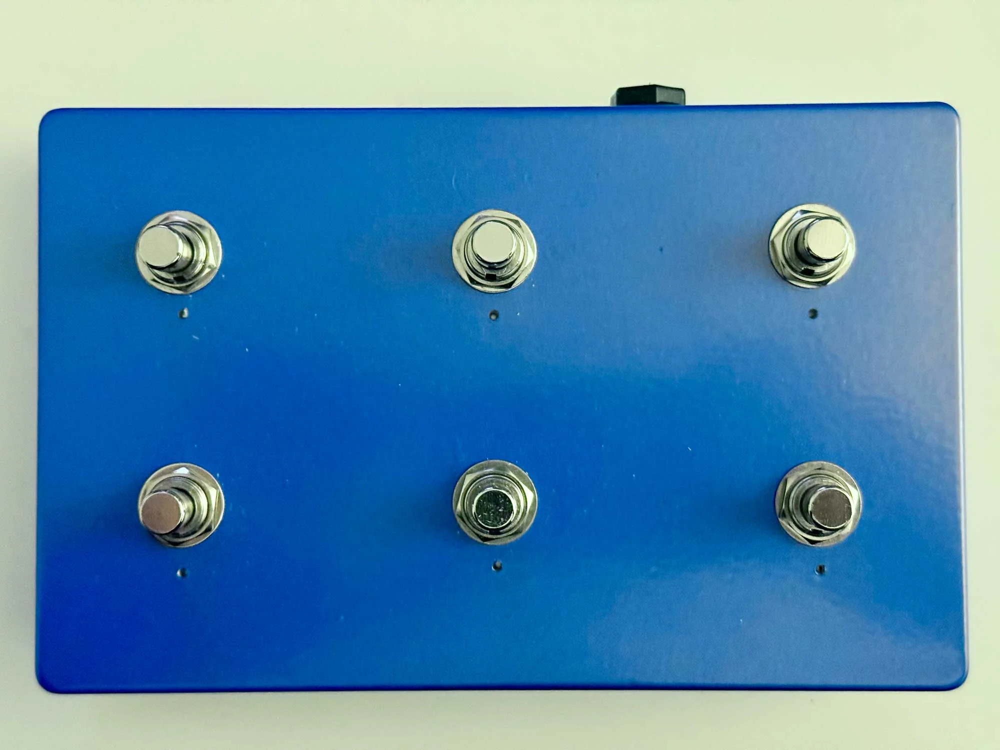 Top down view of the finished controller showing six chrome footswitches on blue aluminum